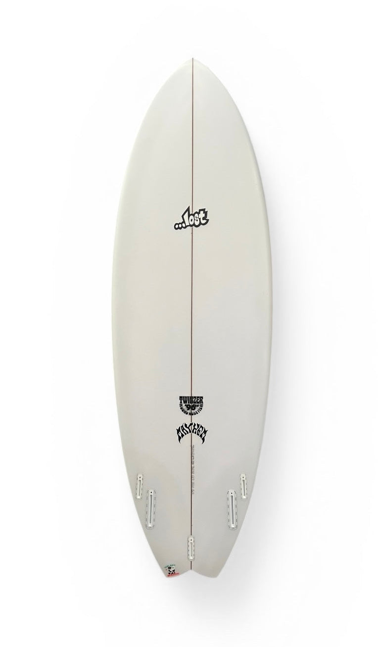 Light cream surfboard with twin fin set, center seam line, black graphic logo.