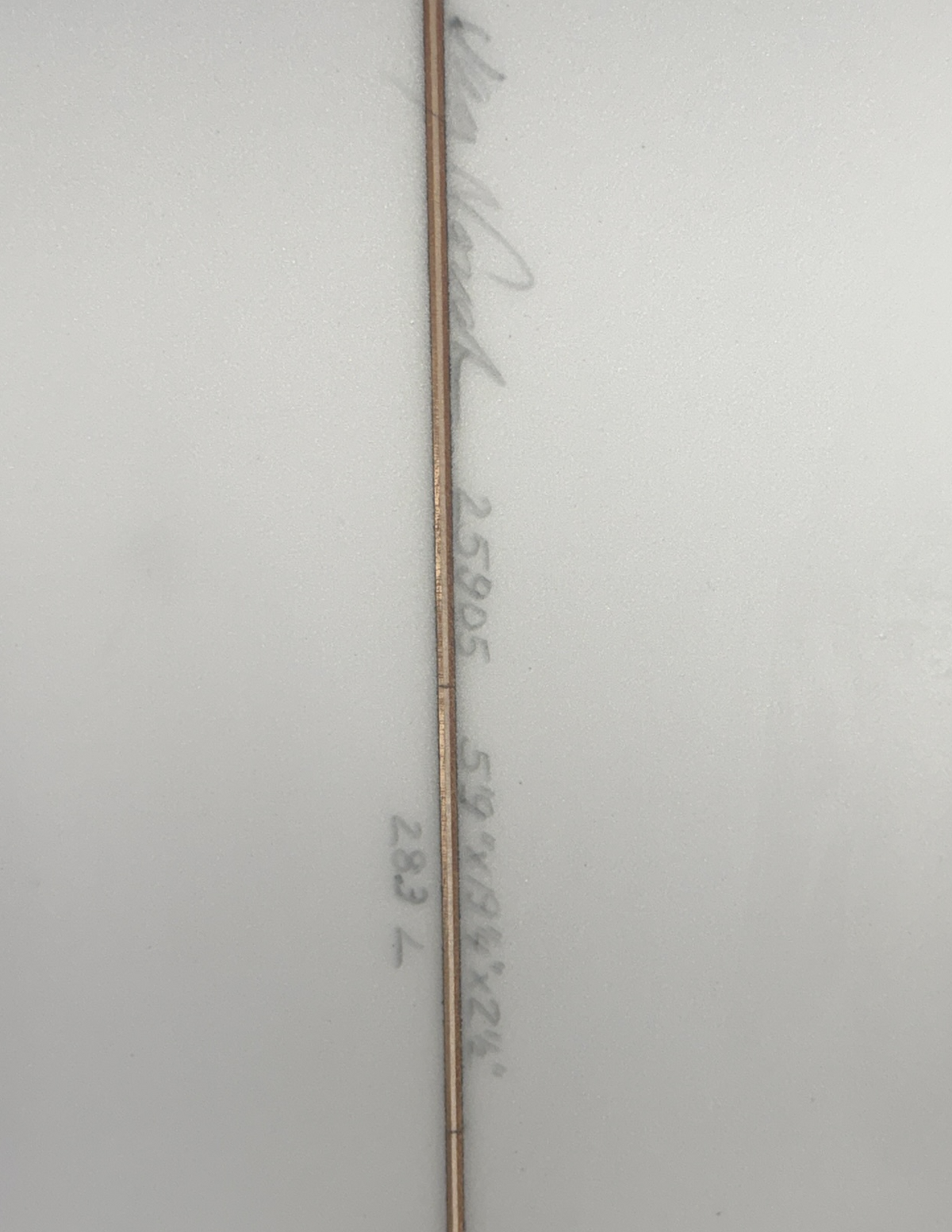The underside of a white surfboard that includes writing of the boards dimensions.