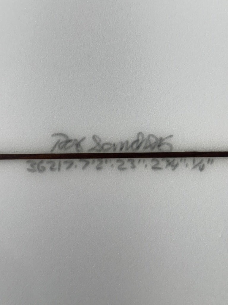 Signature and dimensions on bottom of white surfboard.   