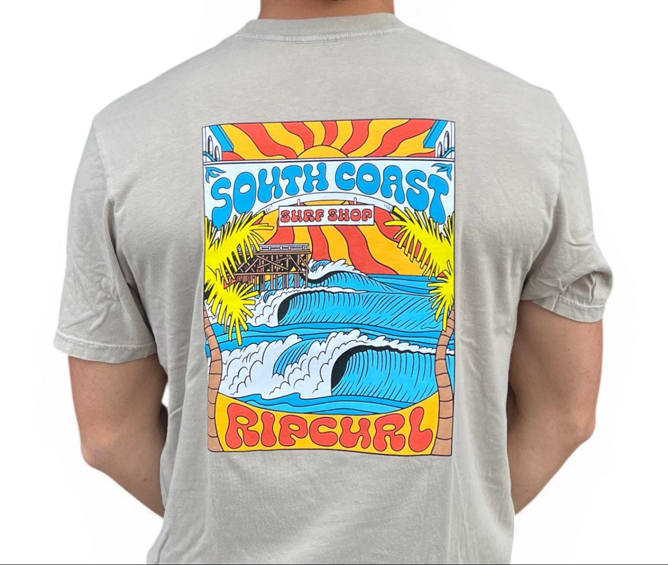 Person wearing a gray t-shirt with a colorful 'South Coast Rip Curl' graphic on the back.
