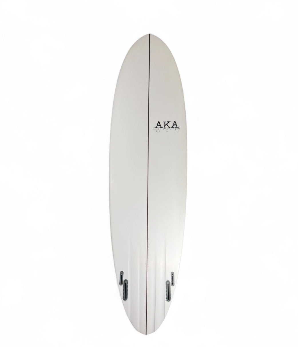 A white surfboard with a black AKA logo printed on the right center, shown floating against a solid white background.