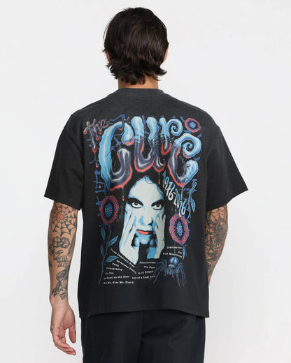 RVCA x The Cure Black T-Shirt modeled from behind, showcasing a relaxed fit and large colorful back graphic featuring Robert Smith and The Cure band lettering.