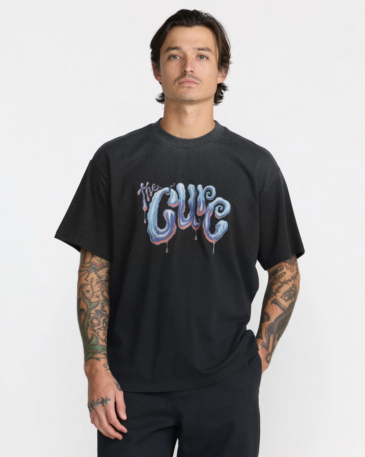 RVCA x The Cure Black Graphic T-Shirt modeled from the front, featuring a relaxed fit, crew neckline, and colorful psychedelic The Cure chest logo.
