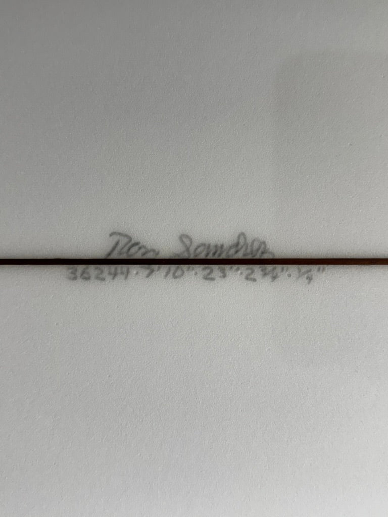 Signature and Dimensions on bottom of white surfboard. 