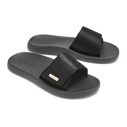 Pair of Cobian Ibiza Slide Sandals in Black featuring wide textured straps, gold logo accents, and contoured footbeds.