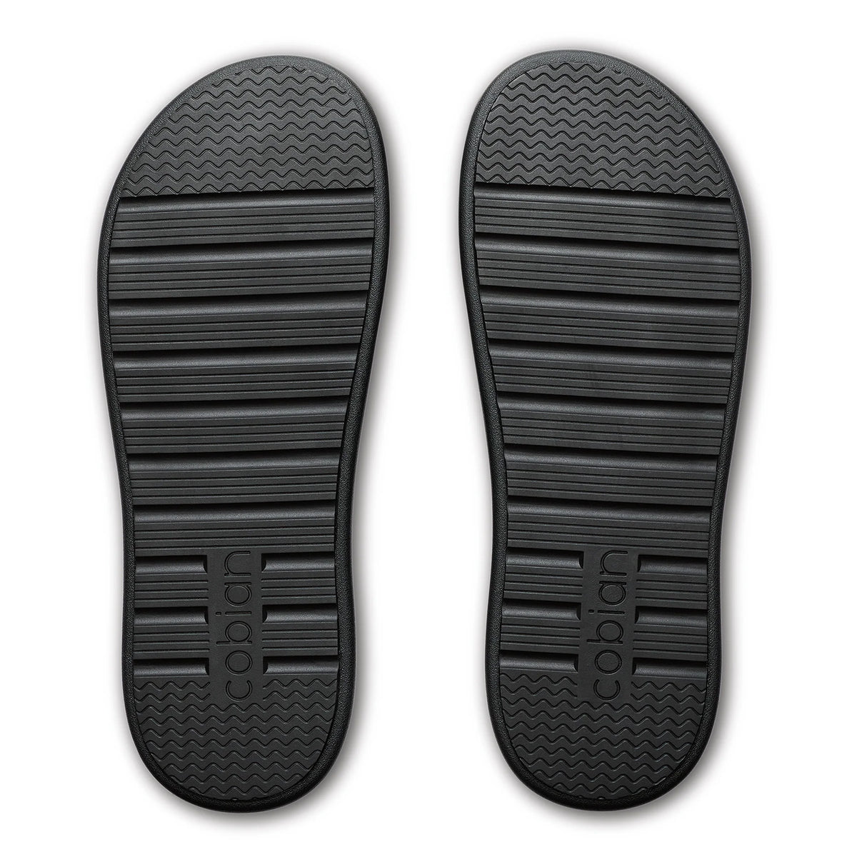Bottom view of Cobian Ibiza Slide Sandals in Black showing the textured rubber outsoles with wave-pattern traction and Cobian branding.