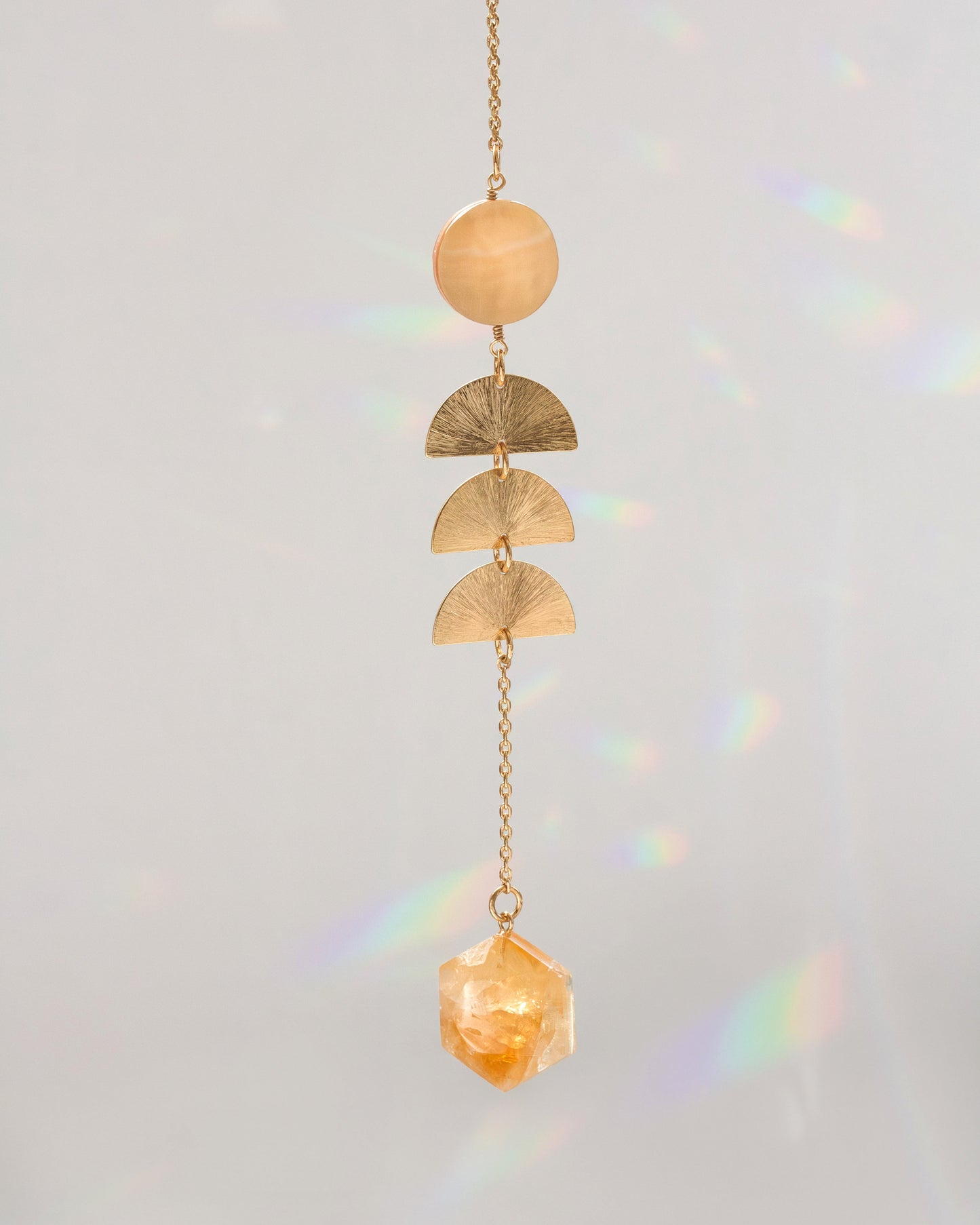 Warm pearl mobile with gold chain, stacked crescent discs, and faceted amber crystal charm