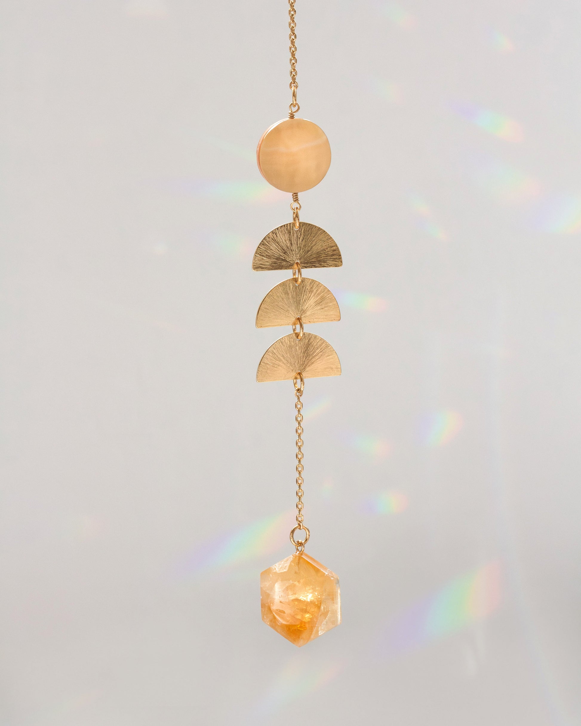 Warm pearl mobile with gold chain, stacked crescent discs, and faceted amber crystal charm