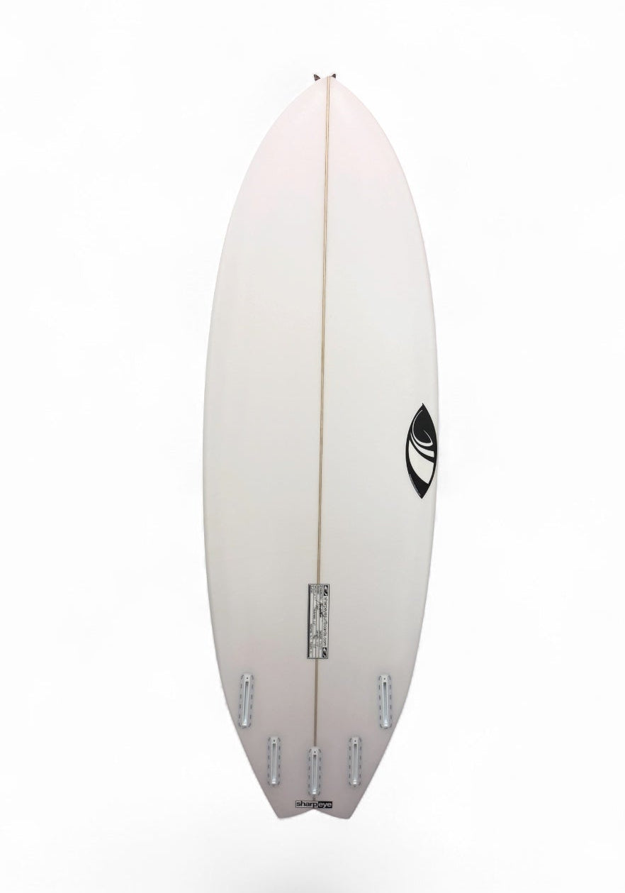 A white surfboard shown from the bottom side, featuring a central stringer and a black circular logo near the tail, set against a plain white background.