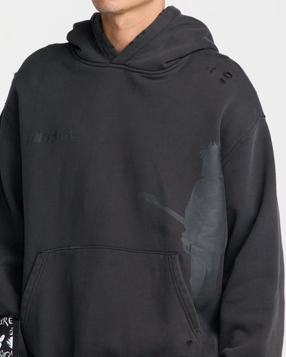 Close-up of The Cure Hoodie in washed black featuring tonal band logo, guitarist silhouette graphic, distressed shoulder details, and front kangaroo pocket.