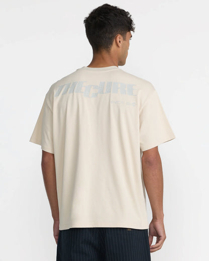 RVCA x The Cure Cream T-Shirt modeled from behind, showcasing the relaxed fit, oversized The Cure back graphic, and subtle RVCA branding.