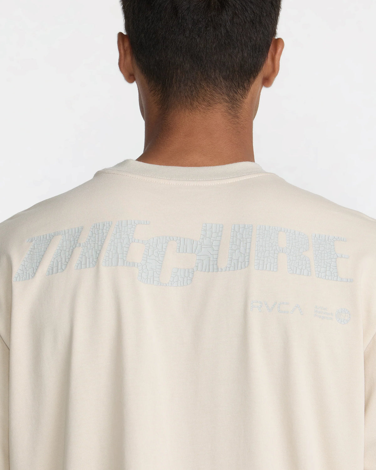 Close-up of RVCA x The Cure Tee in cream highlighting the large cracked-texture The Cure back print with RVCA and Artist Network Program branding.