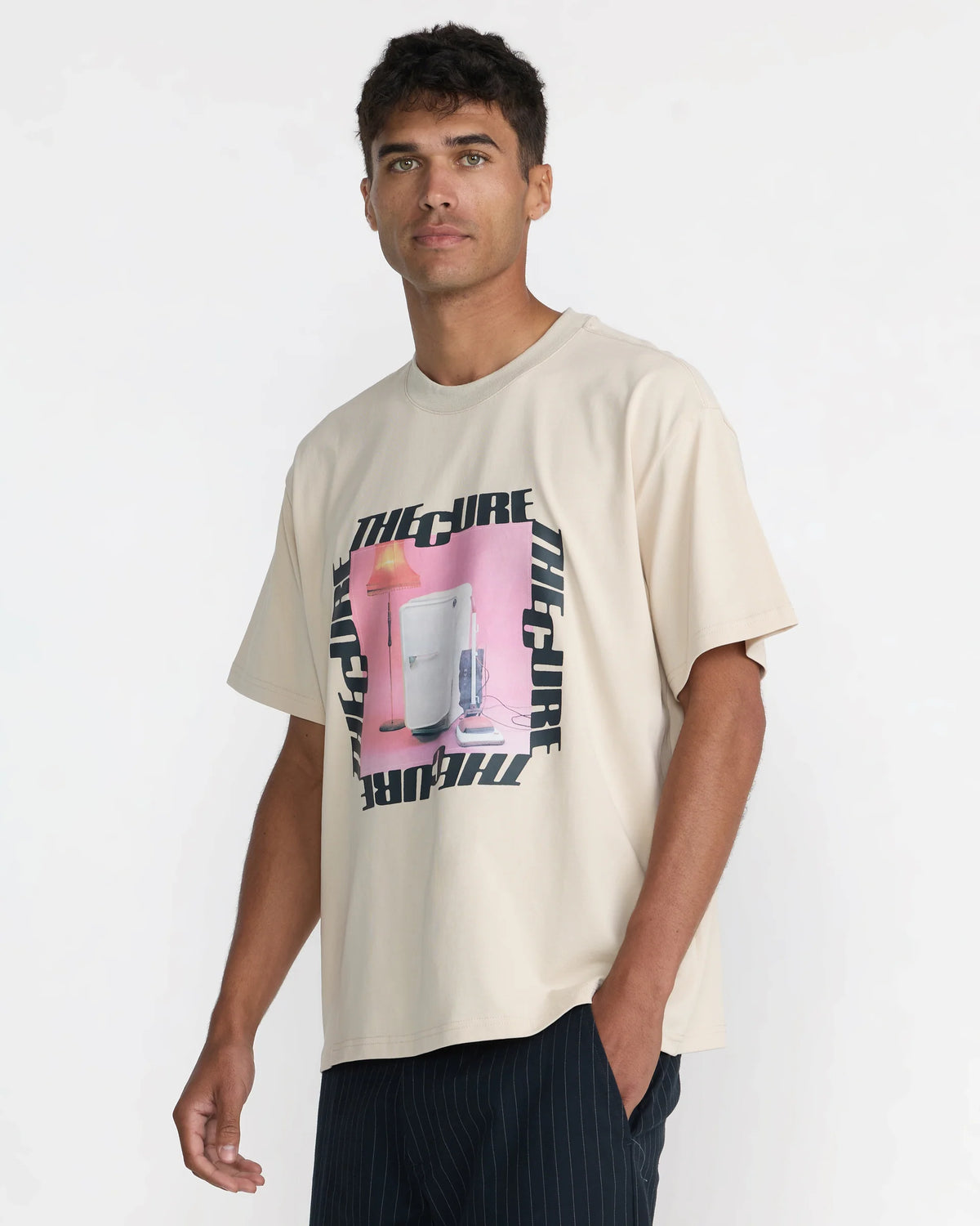 RVCA x The Cure Cream Graphic Tee modeled from an angled front view, highlighting the relaxed silhouette, short sleeves, and vintage-inspired band artwork.